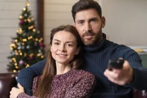 Dos personas viendo la televisión en un ambiente navideño